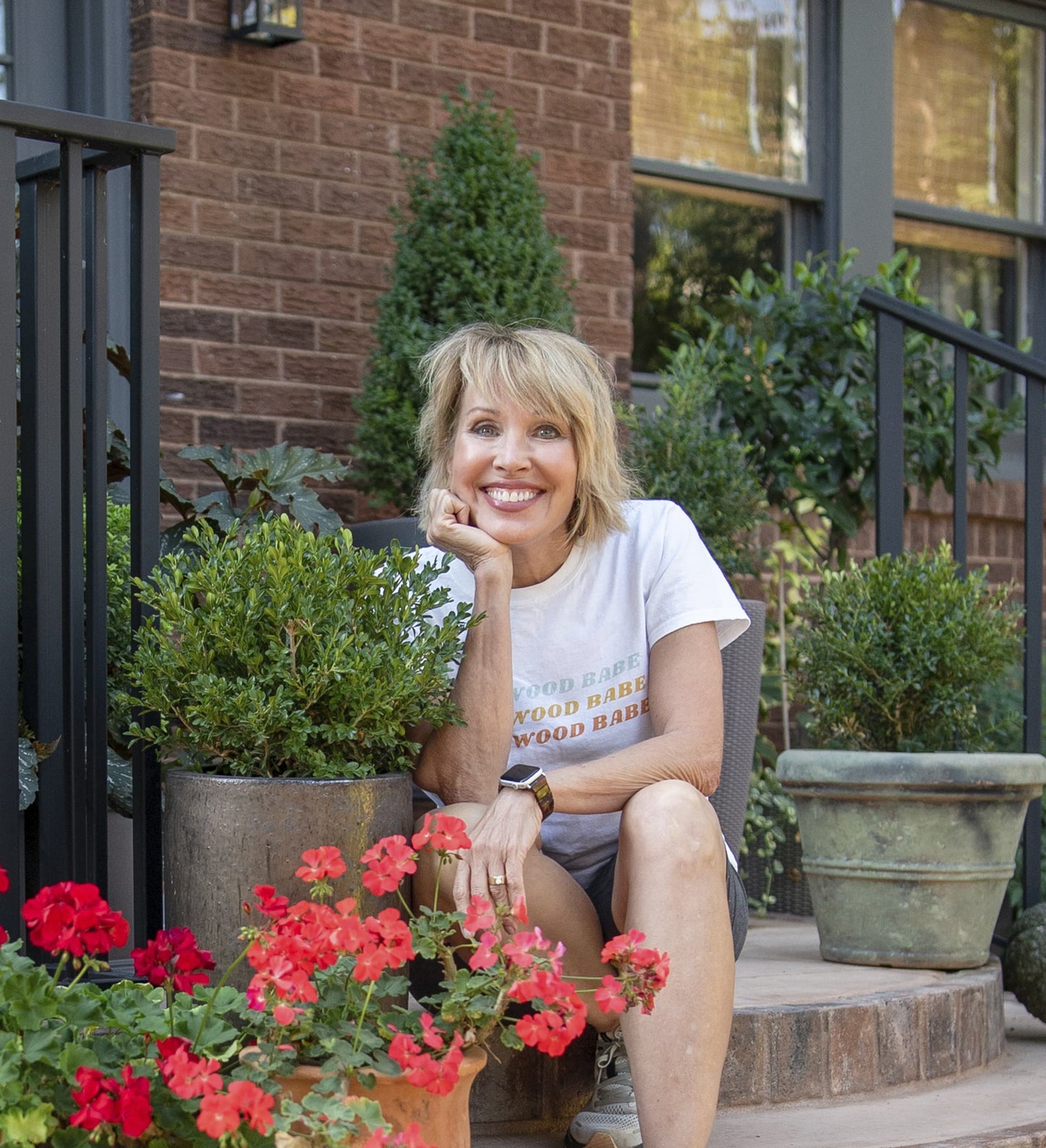 Linda Vater sitting on a step beside a Better Boxwood container planting